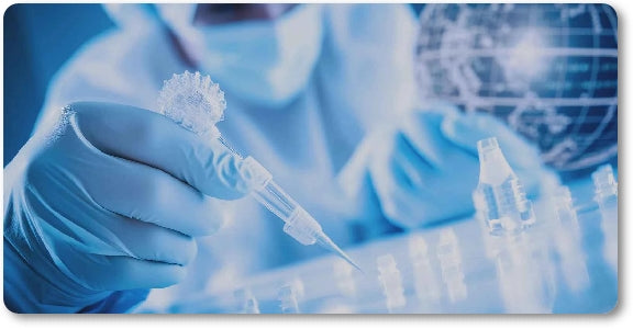 A Person in a Blue Lab Coat, Mask and Gloves Using a Clear Pipette in a Blue Lab